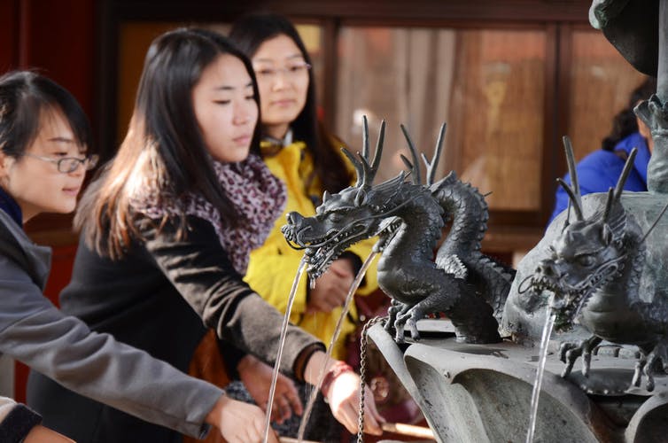 East Asian religious people at a sacred fountain.
